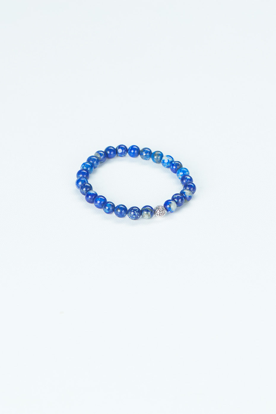 A beaded bracelet in that is in the center of the image, made of a dark blue stone.