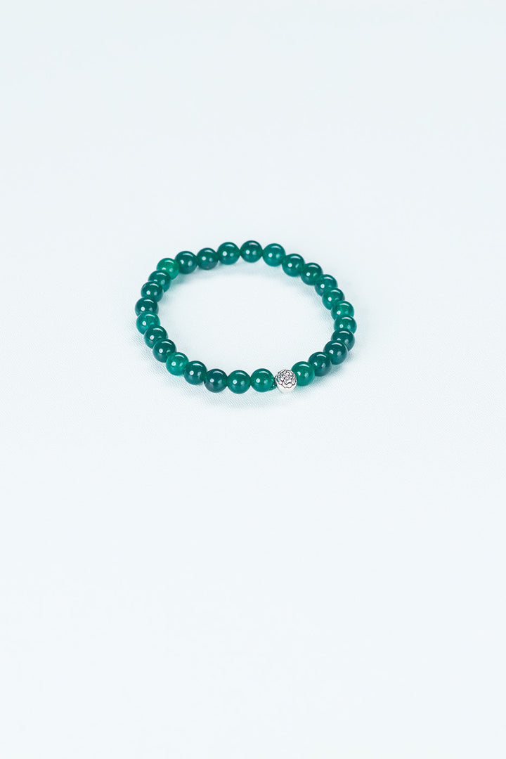 A beaded bracelet that is in the center of the image, made of a green stone.