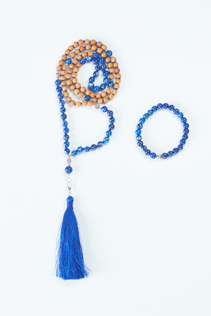 Two pieces of jewelry are shown: on the left a beaded necklace made of Sandalwood and a dark blue stone, with a dark blue tassel on the bottom, and on the right a beaded bracelet made of a dark blue stone